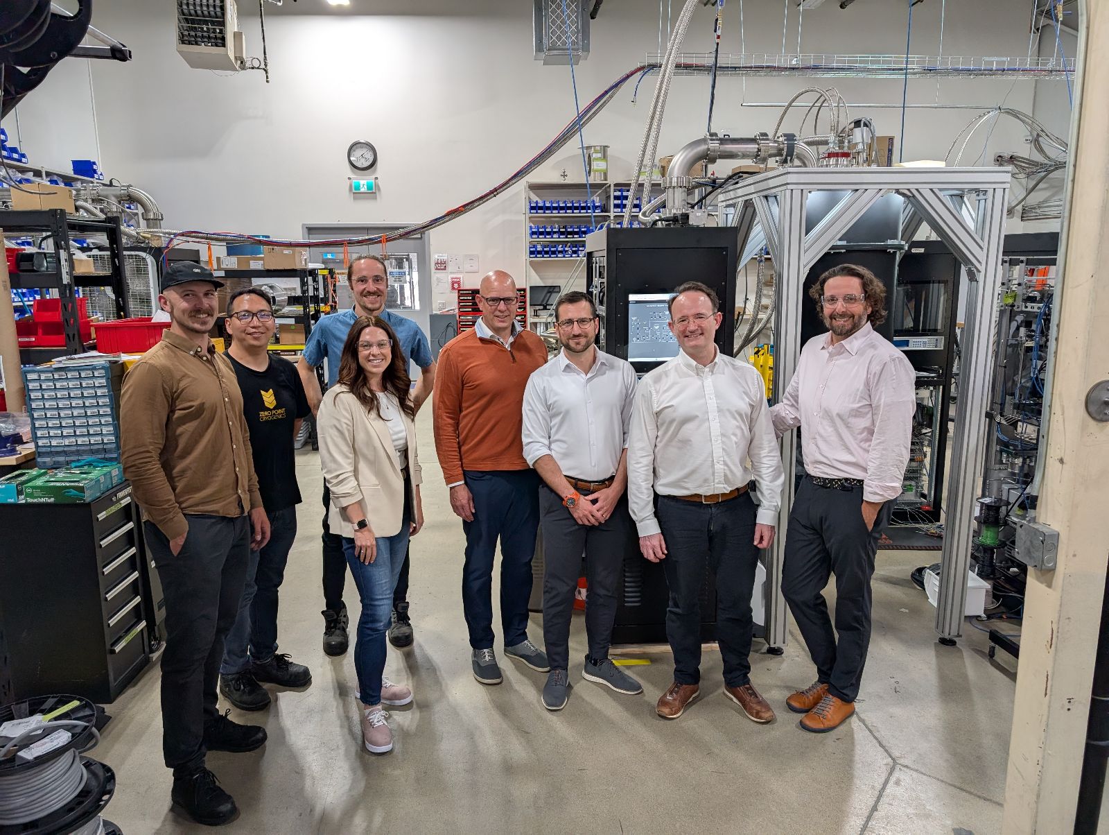 A group photo of Quantum Machines team members and Zero Point Cryogenics staff standing together inside the ZPC facility, surrounded by cryogenic equipment and workstations.